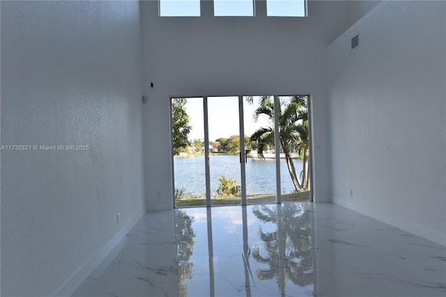 spare room with a high ceiling, plenty of natural light, and a water view