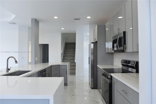 kitchen with sink, stainless steel appliances, kitchen peninsula, and gray cabinetry