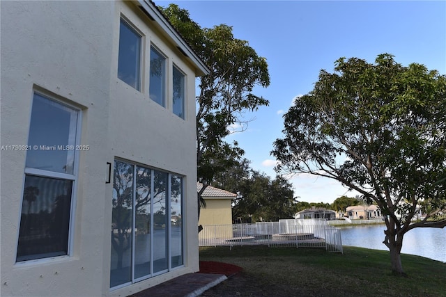 view of property exterior with a water view and a lawn