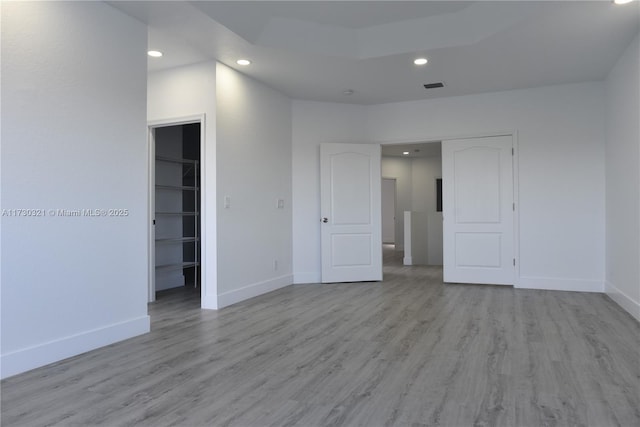 unfurnished bedroom with a closet, a walk in closet, and light wood-type flooring