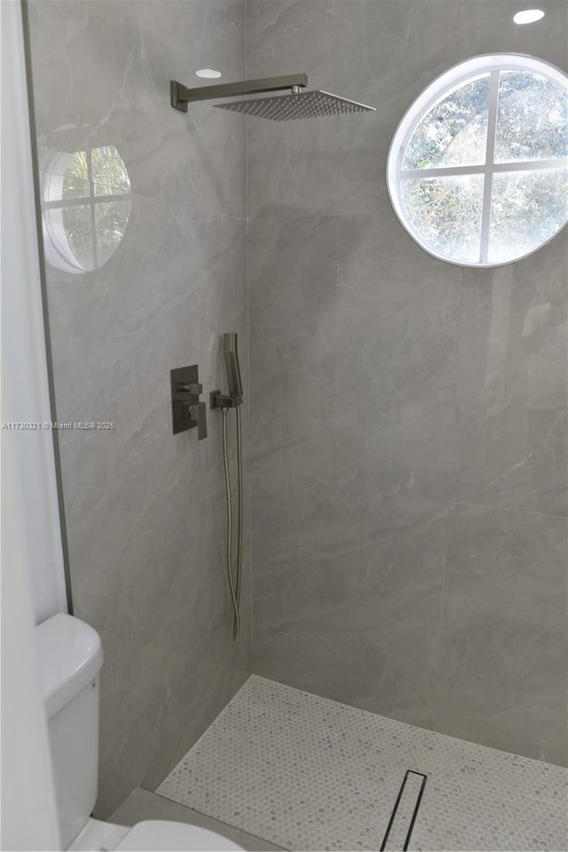 bathroom featuring toilet and a tile shower