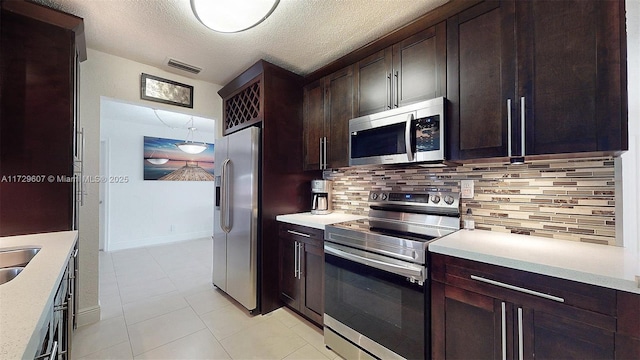 kitchen featuring pendant lighting, appliances with stainless steel finishes, a textured ceiling, decorative backsplash, and light tile patterned floors