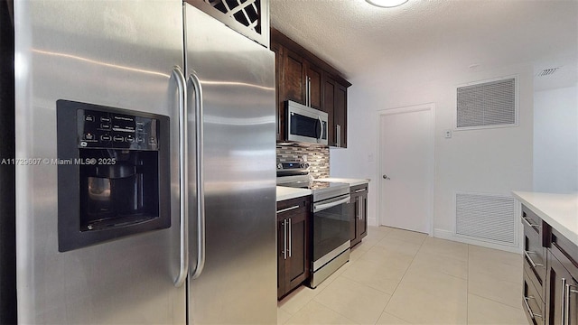 kitchen featuring dark brown cabinets, light tile patterned floors, stainless steel appliances, and tasteful backsplash