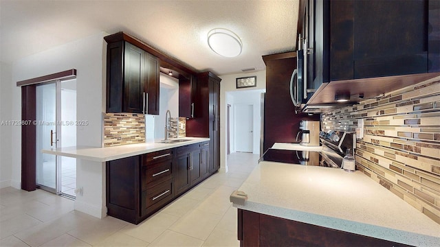 kitchen with kitchen peninsula, sink, electric stove, a textured ceiling, and decorative backsplash