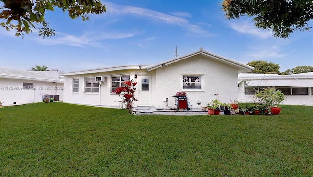 back of property with a wall mounted air conditioner, central AC unit, and a lawn