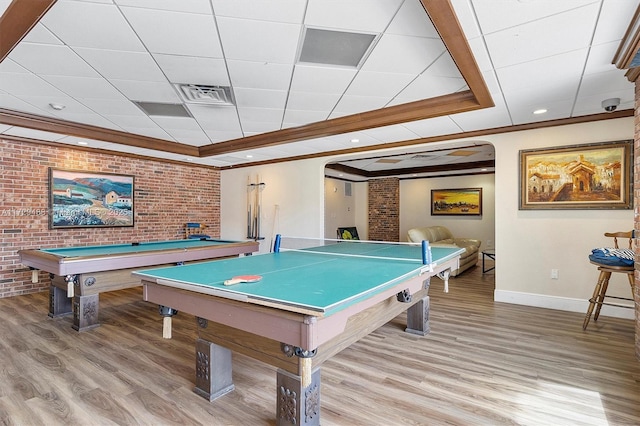 recreation room with brick wall, pool table, light hardwood / wood-style floors, a drop ceiling, and crown molding