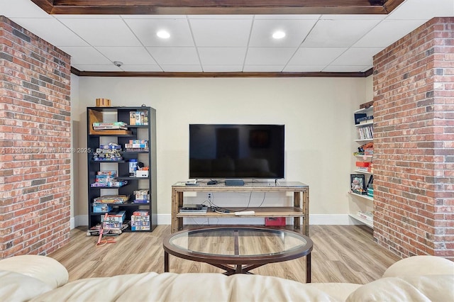 living room with brick wall, wood-type flooring, and crown molding