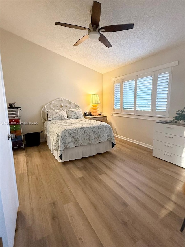 bedroom featuring ceiling fan, light hardwood / wood-style floors, and a textured ceiling