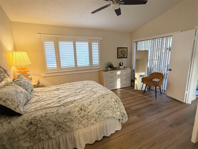 bedroom with ceiling fan, a textured ceiling, dark hardwood / wood-style floors, and vaulted ceiling