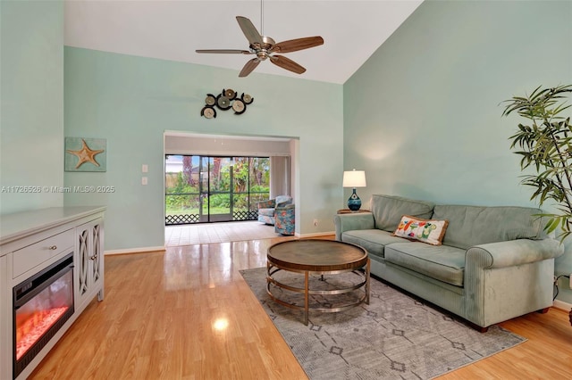 living room with light hardwood / wood-style floors, high vaulted ceiling, and ceiling fan