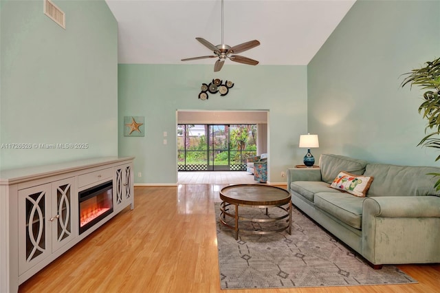 living room with light hardwood / wood-style floors, high vaulted ceiling, and ceiling fan