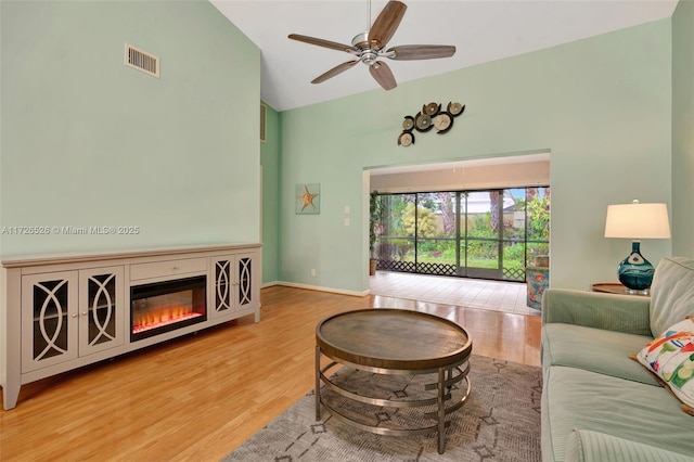 living room with light hardwood / wood-style flooring, high vaulted ceiling, and ceiling fan