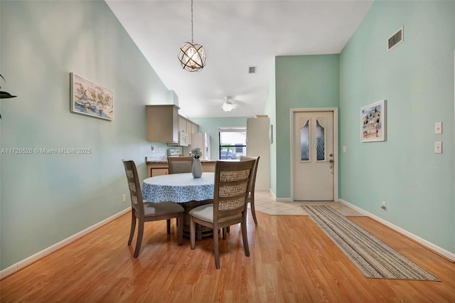 dining area with high vaulted ceiling, light hardwood / wood-style flooring, and ceiling fan