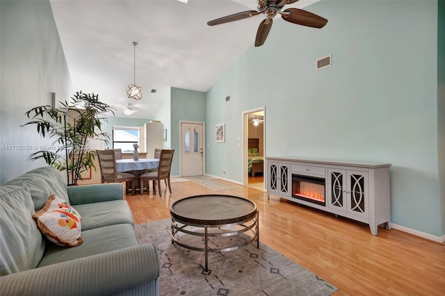 living room with ceiling fan, high vaulted ceiling, and light hardwood / wood-style flooring