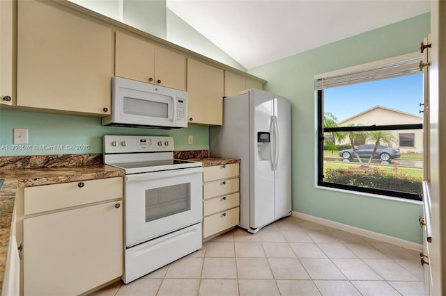 kitchen with white appliances, a wealth of natural light, cream cabinets, and vaulted ceiling