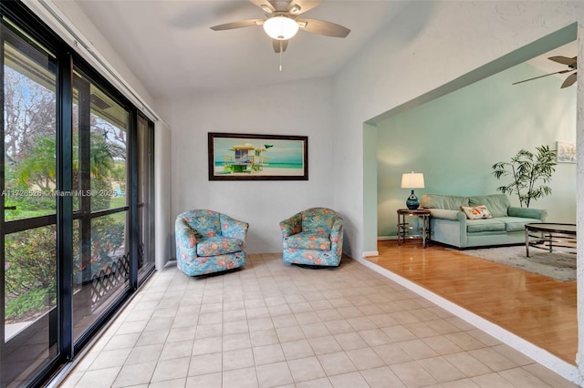 living area with ceiling fan, lofted ceiling, and light tile patterned flooring