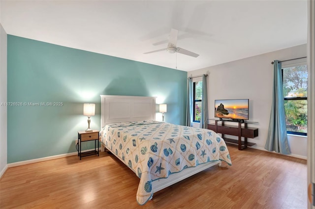 bedroom with ceiling fan, multiple windows, and light hardwood / wood-style flooring