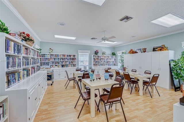 dining room featuring light hardwood / wood-style floors, a textured ceiling, crown molding, and ceiling fan