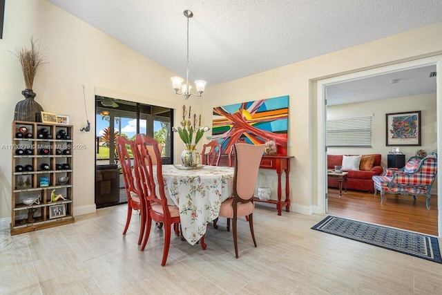 dining area featuring lofted ceiling, light wood-type flooring, a notable chandelier, and a textured ceiling