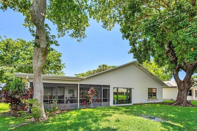 back of house with a sunroom and a lawn