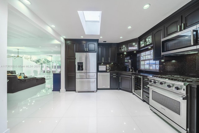 kitchen featuring light tile patterned flooring, appliances with stainless steel finishes, a skylight, wine cooler, and decorative backsplash