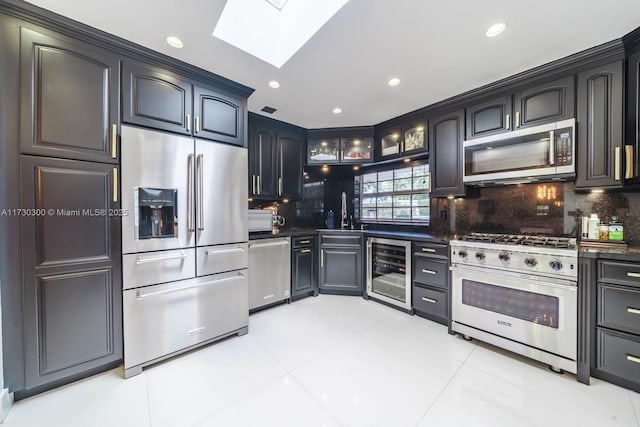 kitchen featuring appliances with stainless steel finishes, a skylight, sink, wine cooler, and decorative backsplash