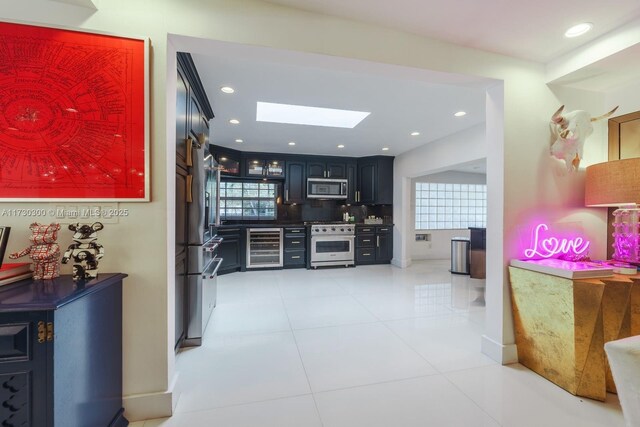 interior space featuring light tile patterned flooring, plenty of natural light, beverage cooler, and a skylight