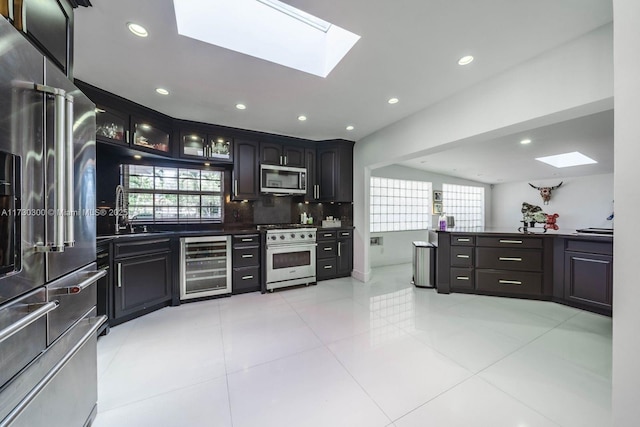 kitchen featuring light tile patterned flooring, dark brown cabinetry, tasteful backsplash, appliances with stainless steel finishes, and beverage cooler