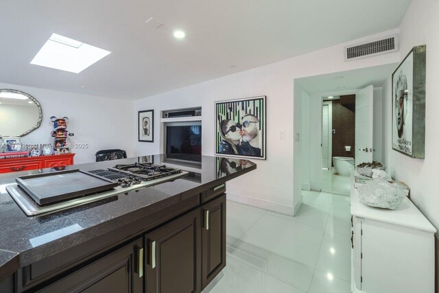 kitchen featuring dark brown cabinetry, light tile patterned floors, and stainless steel gas stovetop