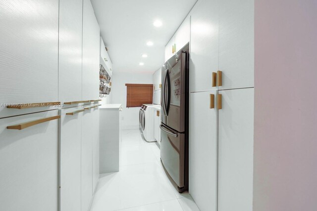 interior space with light tile patterned floors, stainless steel refrigerator, refrigerator, white cabinets, and washer / dryer