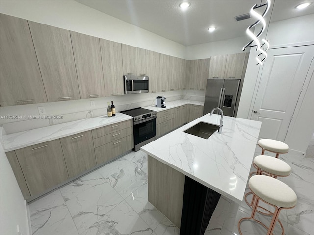 kitchen with sink, light brown cabinets, a kitchen island with sink, and stainless steel appliances