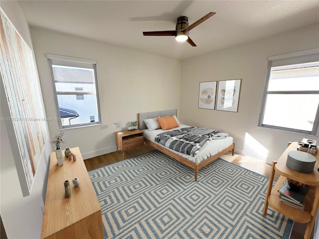 bedroom featuring ceiling fan, multiple windows, and wood-type flooring