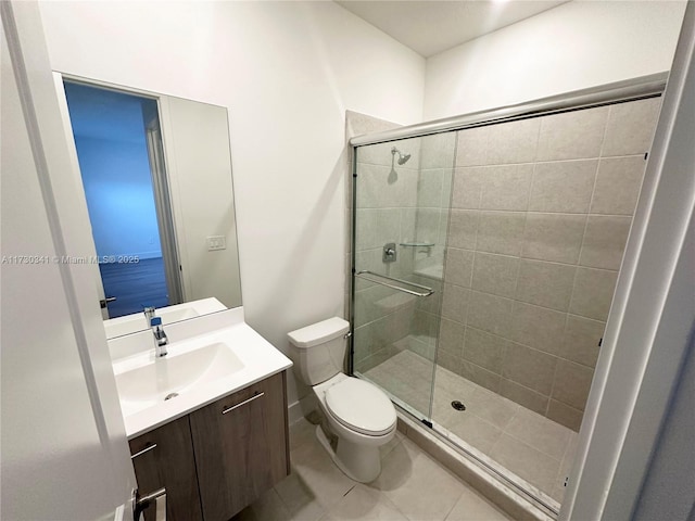 bathroom with vanity, toilet, tile patterned floors, and a shower with door