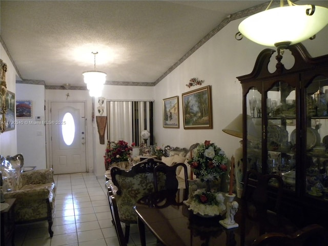 tiled foyer with a textured ceiling, ornamental molding, and vaulted ceiling