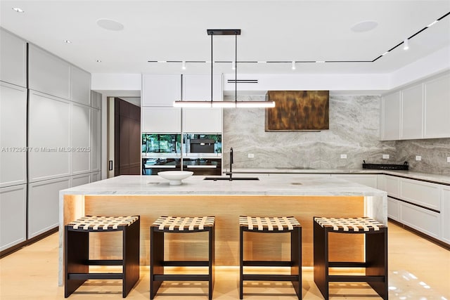 kitchen with sink, pendant lighting, a breakfast bar area, and an island with sink