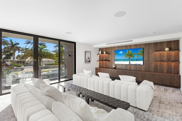 living room with wood walls, a wall of windows, and french doors