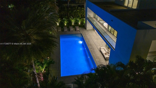 pool at night featuring a patio