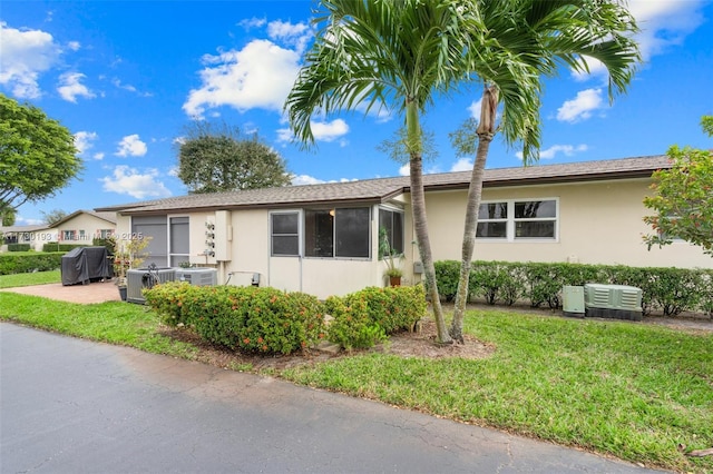 single story home with cooling unit and a front lawn