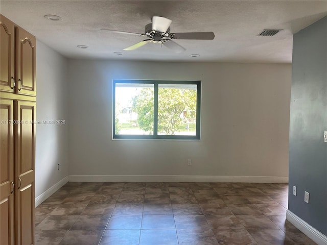 tiled empty room featuring ceiling fan and a textured ceiling