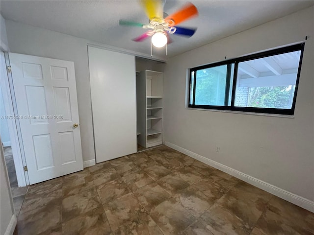 unfurnished bedroom with ceiling fan and a closet