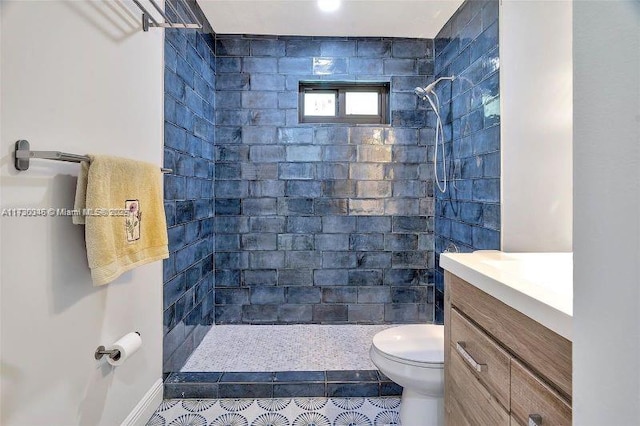 bathroom featuring vanity, toilet, and a tile shower