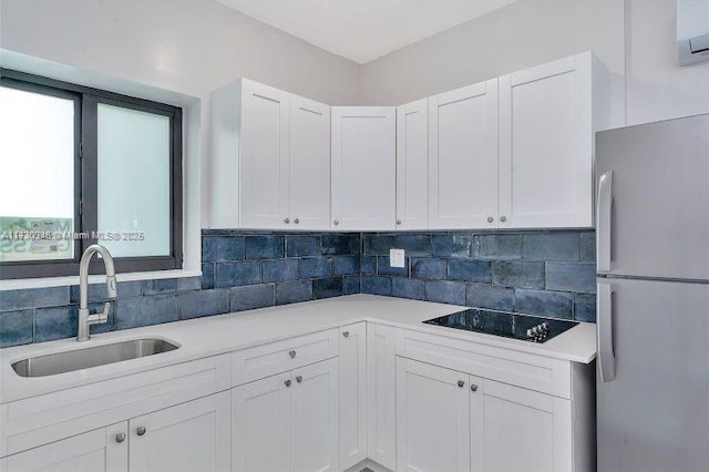 kitchen with tasteful backsplash, sink, white cabinets, white fridge, and black electric stovetop