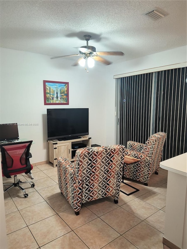 tiled living room with ceiling fan and a textured ceiling