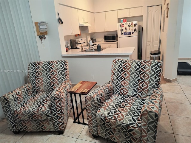 kitchen with electric range oven, white cabinets, white refrigerator, light tile patterned floors, and kitchen peninsula