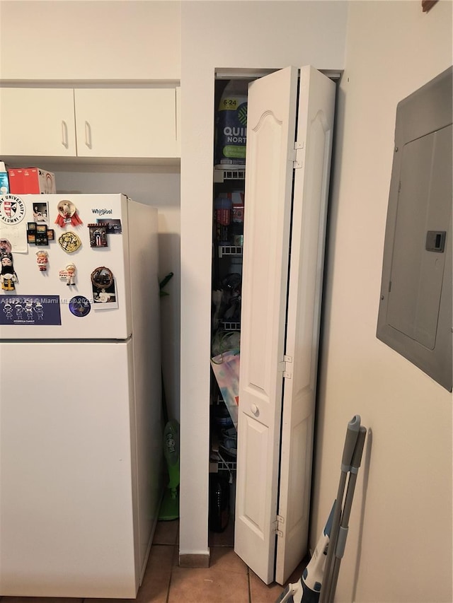 kitchen with white refrigerator, white cabinetry, electric panel, and light tile patterned floors