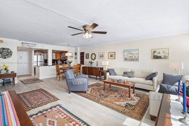 living room with crown molding, light hardwood / wood-style flooring, and ceiling fan