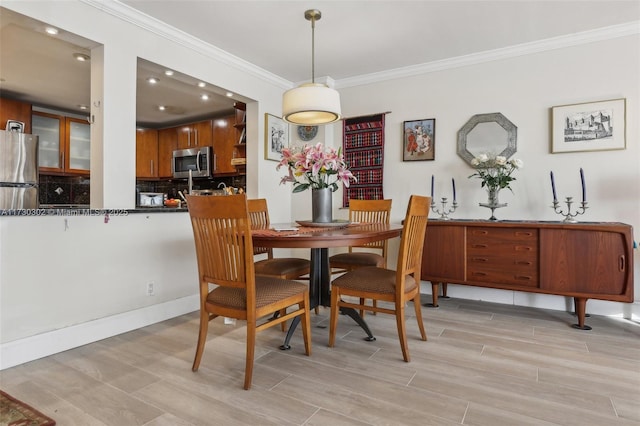 dining area with ornamental molding and light hardwood / wood-style floors