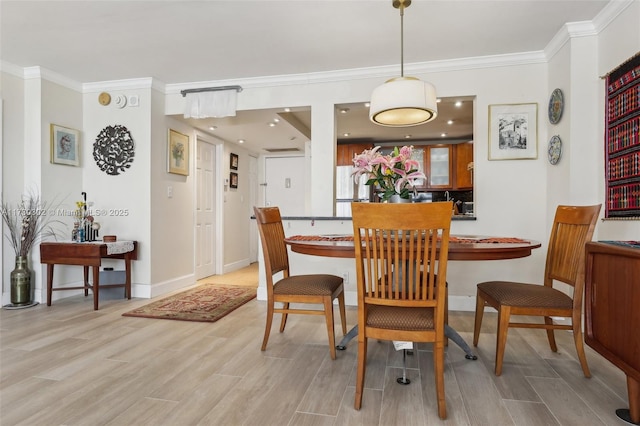 dining room with ornamental molding and light hardwood / wood-style floors