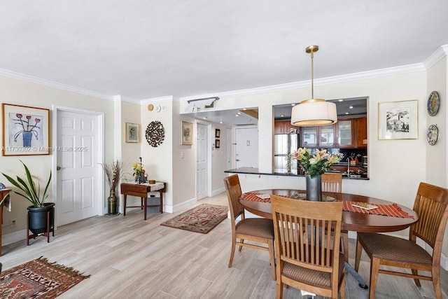 dining space with ornamental molding and light wood-type flooring