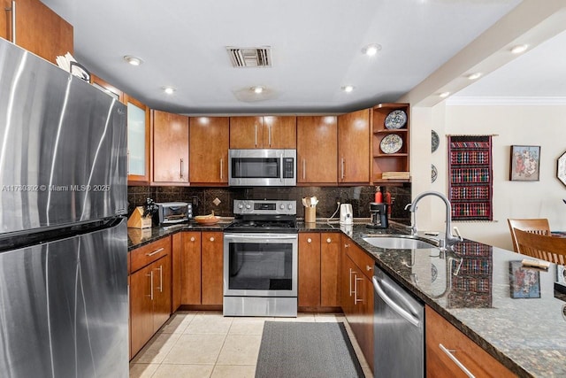 kitchen with appliances with stainless steel finishes, sink, light tile patterned floors, and decorative backsplash